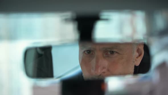 Senior Driver Turning Rear View Mirror, Reflection of Smiling Female Passenger