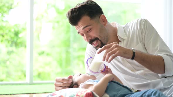 father and baby. A young man is feeding his daughter from a milk bottle