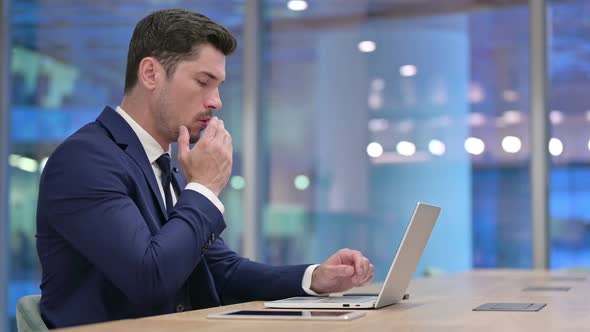 Sick Businessman Coughing While Working on Laptop