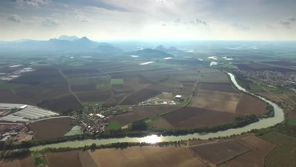 Field, River, Dirt Road, Factory Roof and Little Village Houses in Wide Flat Plain