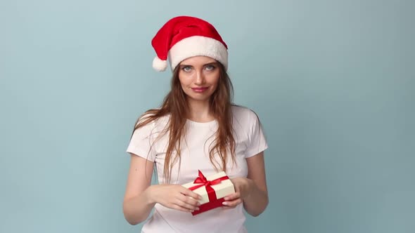 Woman White Tshirt with a Hat of a New Year's Deer with a Small Gift on a Pastel Blue Background