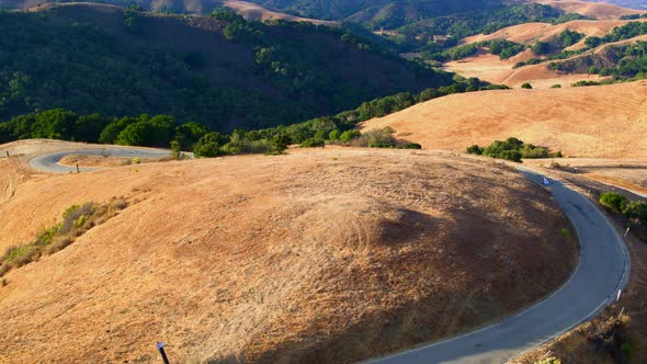 Forward Pan and Tilt Down of a Man Longboarding on State Road 1 Amongst Hills