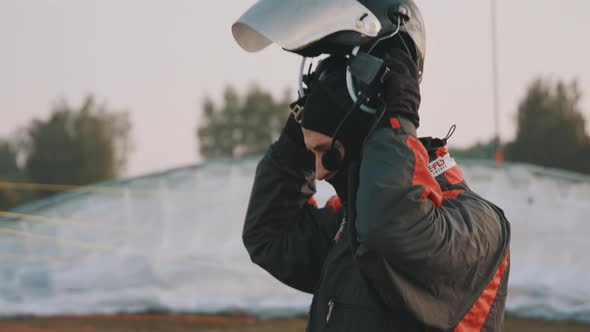 Man Putting on Helmet with Windshield and Communication Equipment