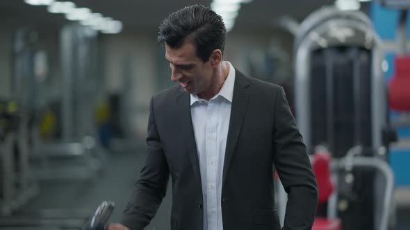 Cheerful Smiling Middle Eastern Sportsman in Suit Lifting Dumbbell Looking at Camera