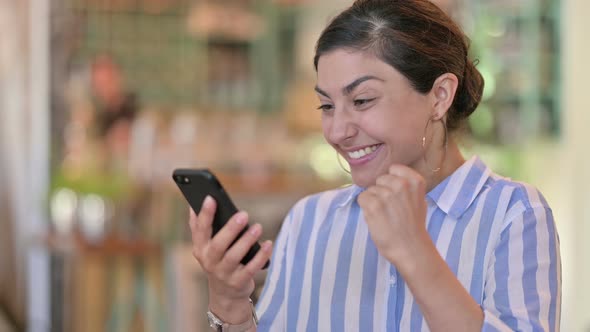 Cheerful Indian Woman Celebrating Success on Smartphone 