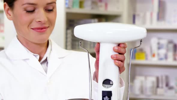 Pharmacist measuring tablets with pharmacy scale