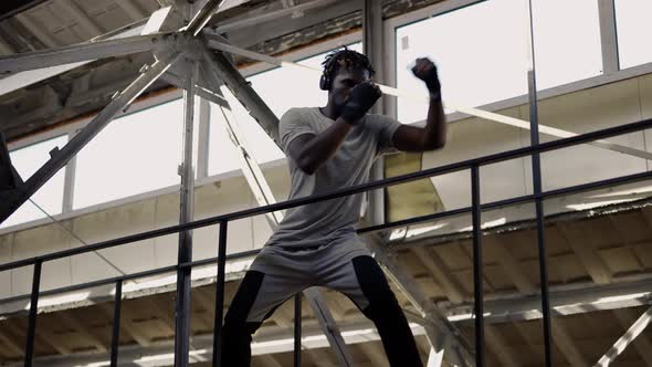 Afro American Young Male Boxer Practicing Shadow Boxing Around the Metal Structures Indoors