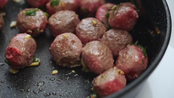 Unrecognizable person cooking meatballs on frying pan with oil