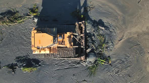 Aerial View on Top Large Bulldozer Cleans the Bottom of the Lake From Thickets and Swamps