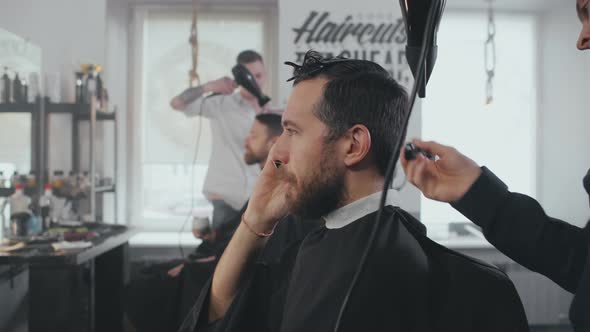 Man Talking on Phone Having His Hair Dried and Groomed in Barbershop