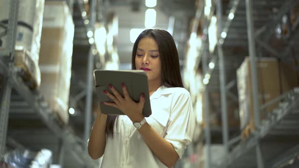 Asian woman warehouse worker checks stock and inventory with digital tablet computer