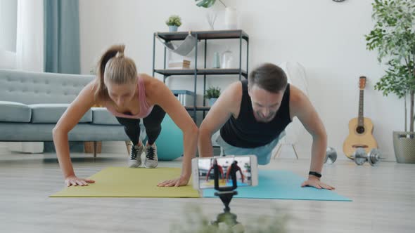 Joyful Couple Bloggers Training at Home and Recording Video with Smartphone Camera