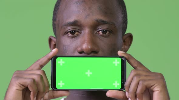 Young African Man Showing Phone Against Green Background