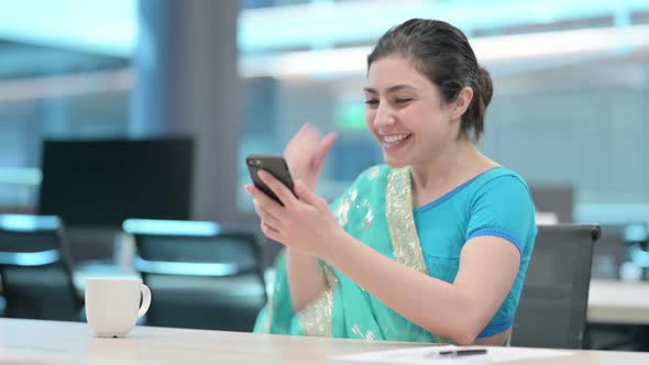 Young Indian Woman Celebrating Success on Smartphone