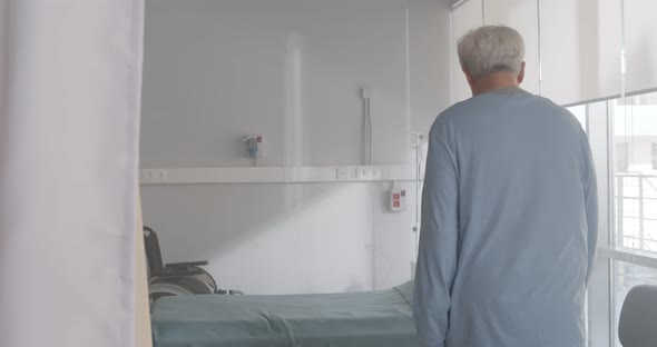 Aged Male Patient Opening Curtain in Hospital Ward and Going to Bed