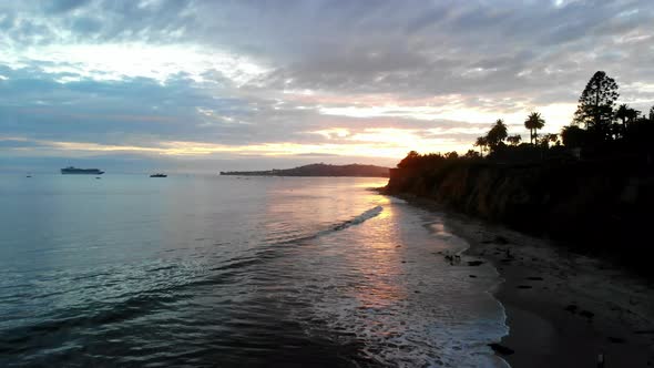 Aerial drone shot at sunset overlooking the Pacific Ocean and California cliffs of Santa Barbara fro