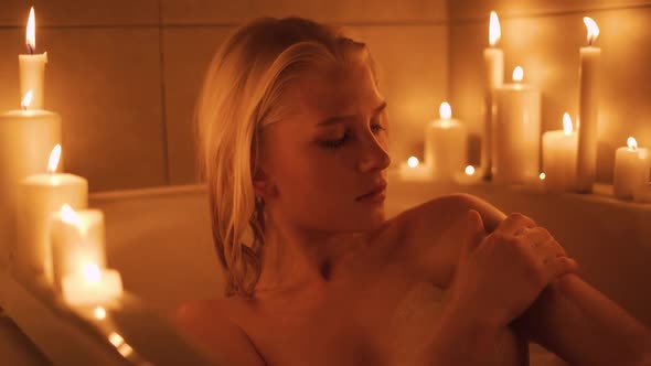 Slow Motion Shot of a Young Woman Having a Bath in the Light of Candles