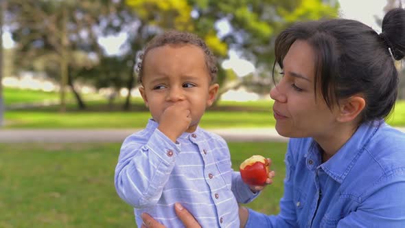 Mixed-race Pretty Mother Looking at Son Eating Apple