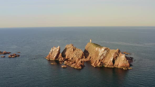 An Abandoned Lighthouse on Top of a Rocky Island at Sunrise