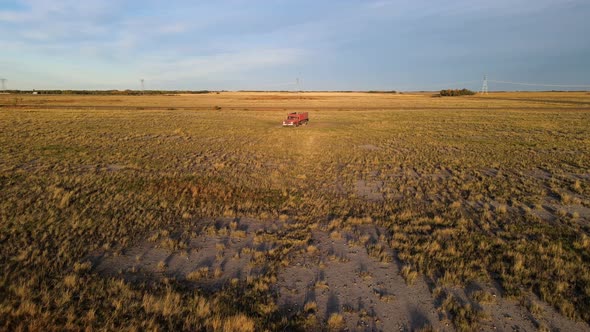 Isolated red truck parked in the middle of farm fields in a large agricultural field in the USA. Aer
