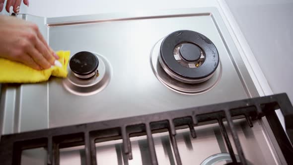 Woman cleaning gas stove. Hand of woman cleaning gas cooker with sponge in the kitchen