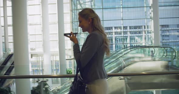 Businesswoman talking on mobile phone in the lobby at office 4k