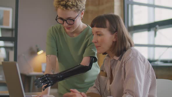 Businesswoman with Prosthetic Arm Helping Colleague in Office