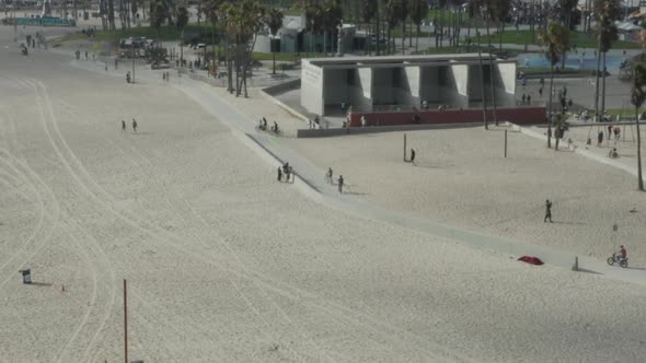 AERIAL: Circling Around Venice Beach Skatepark and Boardwalk with Palm Trees and Bike Lane, Sunny