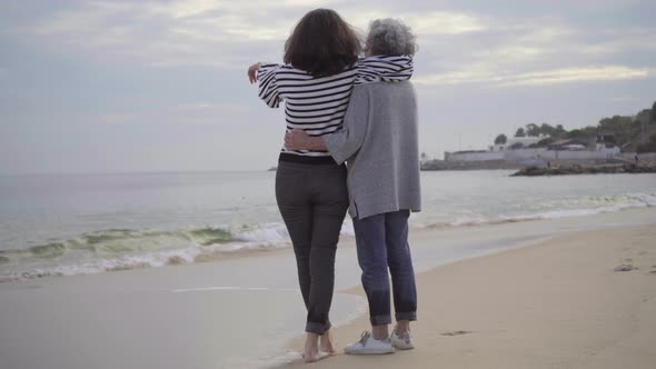 Two Smiling Women Hugging on Seacoast