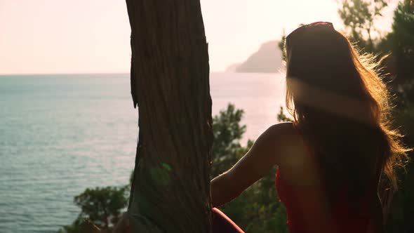 Young Athletic Girl with Long Hair Sits Amid Beautiful Scenery the Sea and the Sunset