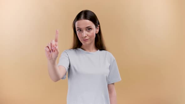 Young Caucasian Woman Over Plain Beige Background Showing Attention Sign with Pointed Finger Beige