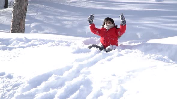 Cute Asian Child Wearing Winter Clothes Playing On Snow In The Park 