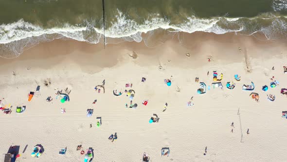 Beach showing colourful umbrellas and people relaxing on a summer day. Baltic Sea. Aerial view. Hel