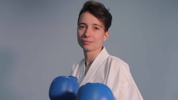 Karate and Taekwondo Woman in White Kimono with Black Belt Trains Punches and Kicks in Blue Sports