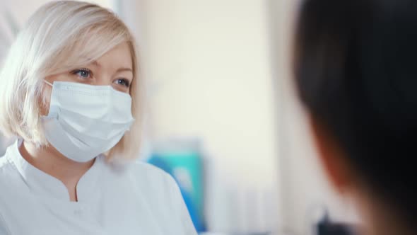 Medical Staff Woman in a Sterile Mask Talking to a Patient and Smiling