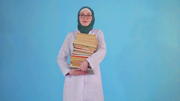 Young Muslim Medical Student with Books on Blue Background