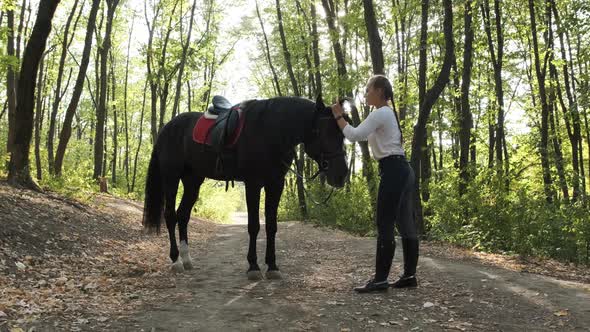 Young Beauty Girl Gently Caressing Her Horse in the Park.