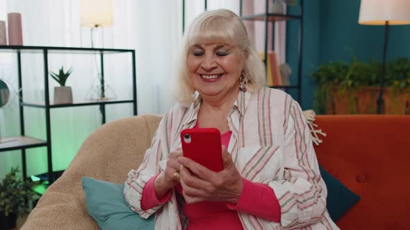 Senior Old Grandparent Works on Mobile Phone Sends Messages Makes Online Purchases at Home Sofa