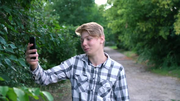 a Young Teenager Man of Caucasian Ethnicity in a Gray Shirt in a Cage Stands on the Street in the