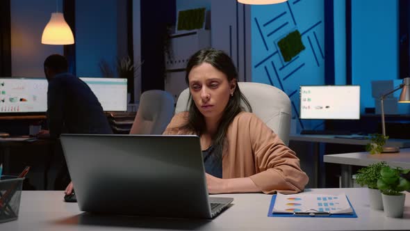 Workaholic Tired Businesswoman Typing Financial Statistics on Laptop