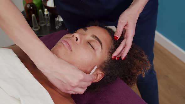 Cosmetologist Using Massage Tool Gua Sha for Face Lifting Indoors