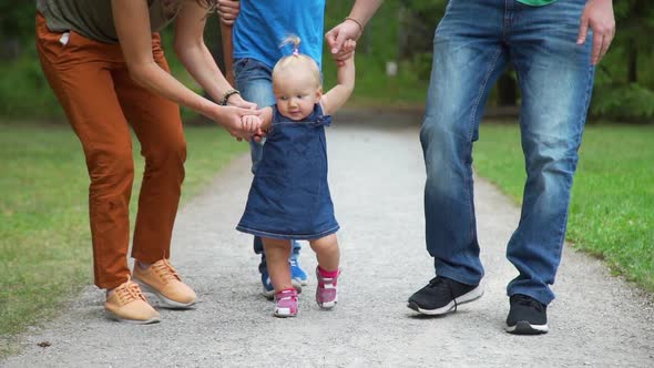 Family Guiding Baby Girl with the First Steps