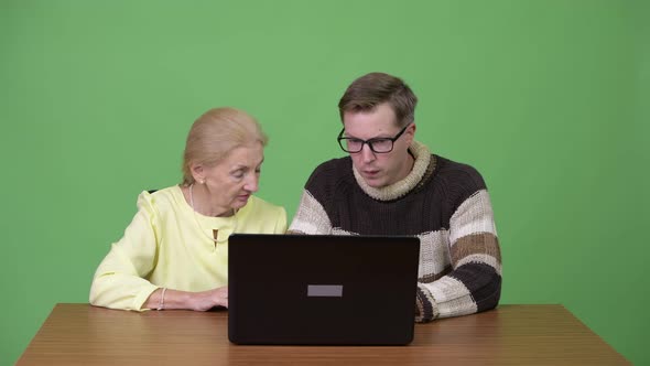 Senior Businesswoman and Young Handsome Man Using Laptop Together