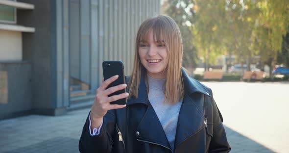 Fashionable Girl with Short Hair While Holding Smartphone Talking By Video Chat Onthe City
