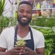 Happy AfricanAmerican Man Gardener Smiling at Camera While Working in Flower Garden Shop - VideoHive Item for Sale