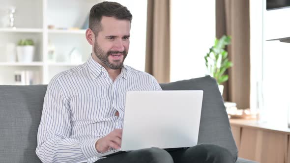 Excited Businessman Celebrating Success on Laptop at Home