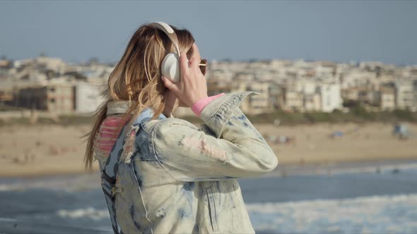 Blonde Woman with Wearing Wireless Headphones Listening Music Enjoying Sunset