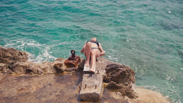 Woman Sunbathes By the Ocean