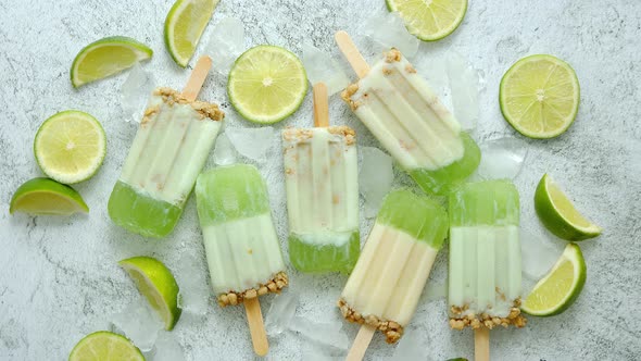 Lime and Cream Homemade Popsicles or Ice Creams Placed with Ice Cubes on Gray Stone Backdrop