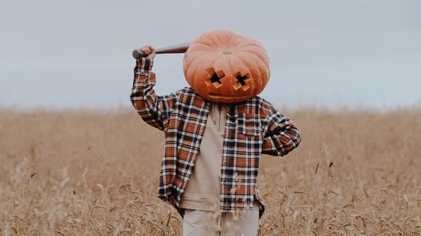 On a Halloween Holiday a Man with a Large Orange Pumpkin on His Head and a Bat in His Hands is Angry